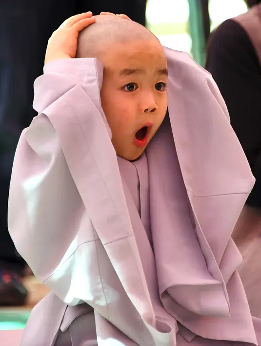 Ekspresi lucu biksu cilik saat ikut upacara Buddha Monks di kuil Jogye, Seoul, Rabu (19/4). (AFP PHOTO / JUNG Yeon-Je)