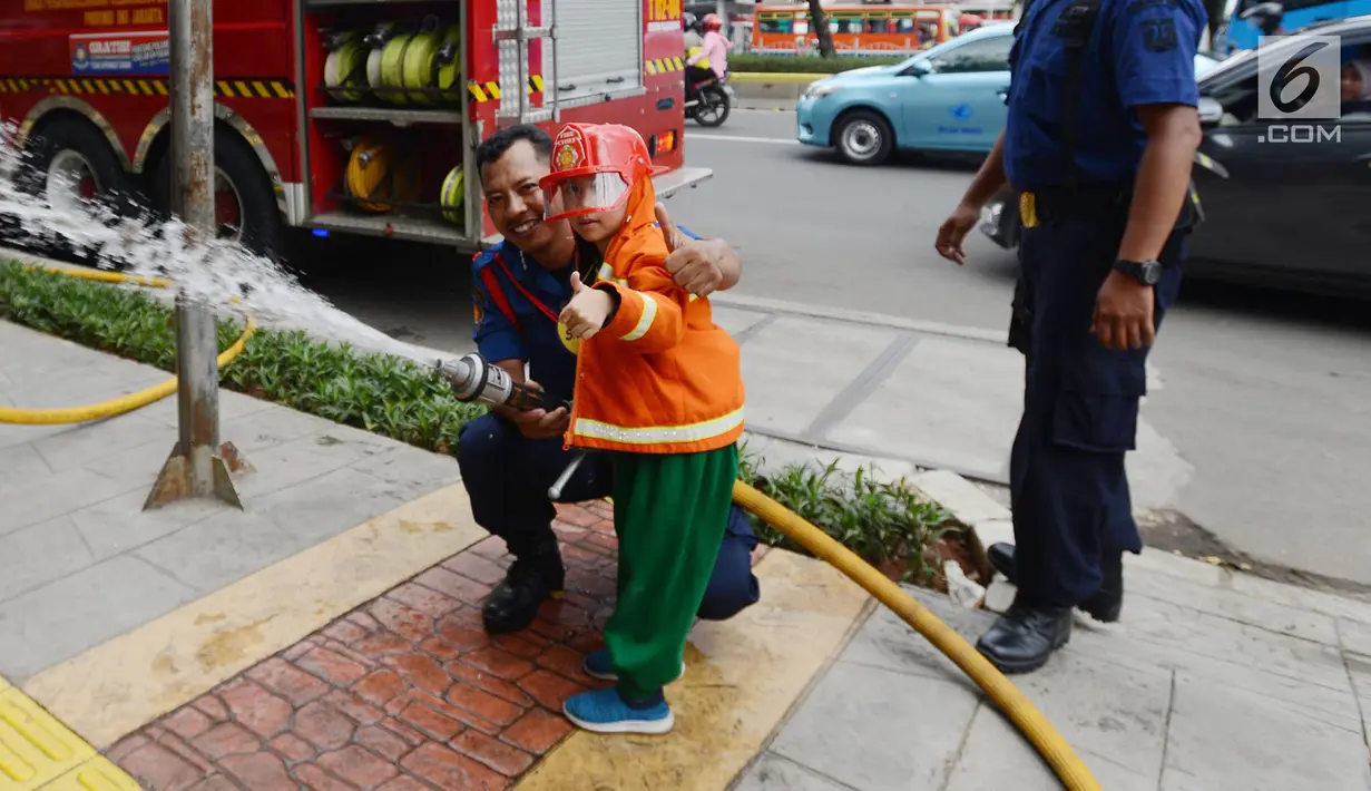 Petugas pemadam kebakaran berpose dengan anak TK saat mengajari cara memadamkan api di Jakarta, Kamis (21/3). Kegiatan ini bertujuan mengenalkan profesi pemadam kebakaran dan memberi pengetahuan proses pemadaman api kepada anak. (merdeka.com/Imam Buhori)