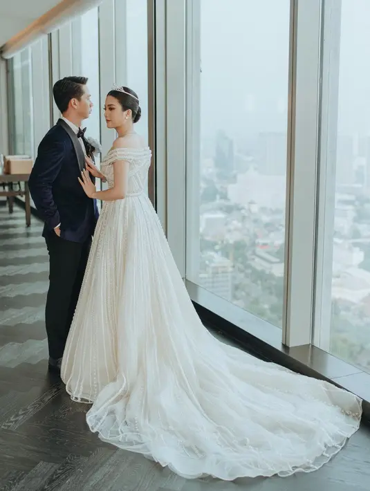 Gaun princess lainnya dari acara resepsi Valencia dan Kevin Sanjaya di Jakarta. Off the shoulder dress putih dengan rok yang menjuntai hingga ke lantai. Lagi, Valencia bak putri raja mengenakan tiara dan berbagai aksesori berlian yang mewah. Foto: Instagram.
