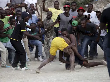 Para pria Haiti sedang beradu ketahanan pada ajang Gulat yang disebut Pinge wrestling competition di Port-au-Prince, Haiti, Sabtu (26/3/2016). Acara ini untuk memperingati Paskah di Haiti. (REUTERS/Andres Martinez Casares)