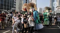 Warga berfoto dengan ondel-ondel yang tampil dalam pawai budaya dan kesenian Betawi saat Hari Bebas Kendaraan Bermotor (HBKB) atau car free day (CFD) di Jalan MH Thamrin, Jakarta, Minggu (19/6/2022). Pawai yang menampilkan berbagai budaya dan kesenian Betawi seperti ondel-ondel, tari topeng, serta tanjidor tersebut digelar dalam rangka menyambut HUT ke-495 DKI Jakarta. (merdeka.com/Iqbal S. Nugroho)