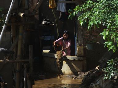 Seorang anak membersihkan rumah dari sisa lumpur di Bukit Duri, Jakarta, Jumat (29/10/2021). Hujan dengan intensitas tinggi beberapa hari lalu membuat aliran sungai ciliwung meluap yang merendam sebagian rumah warga yang tinggal di bantaransungai  tersebut. (merdeka.com/Imam Buhori)