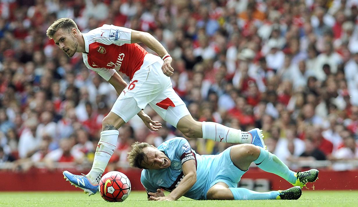 Pemain West Ham, Mark Noble (bawah), berusaha menghentikan langkah Aaron Ramsey dalam pertandingan di Stadion Emirates, London. Minggu (9/8/2015). (EPA/Gerry Penny)