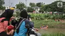 Warga menyaksikan pencarian korban tenggelam di Kanal Banjir Timur, Duren Sawit, Jakarta Timur, Selasa (2/11/2021). Sebelumnya ABP tenggelam dan hanyut terbawa arus saat bermain di saluran air saat hujan deras pada Senin (1/11) siang bersama ketiga temannya. (merdeka.com/Iqbal S. Nugroho)