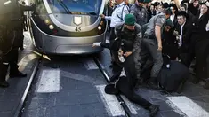 Pasukan keamanan Israel saling tarik-menarik dengan demonstran Yahudi Ultra-Ortodoks yang memblokir jalan utama saat melakukan aksi menentang wajib militer Israel di Yerusalem (17/10). (AFP Photo/Menahem Kahana)
