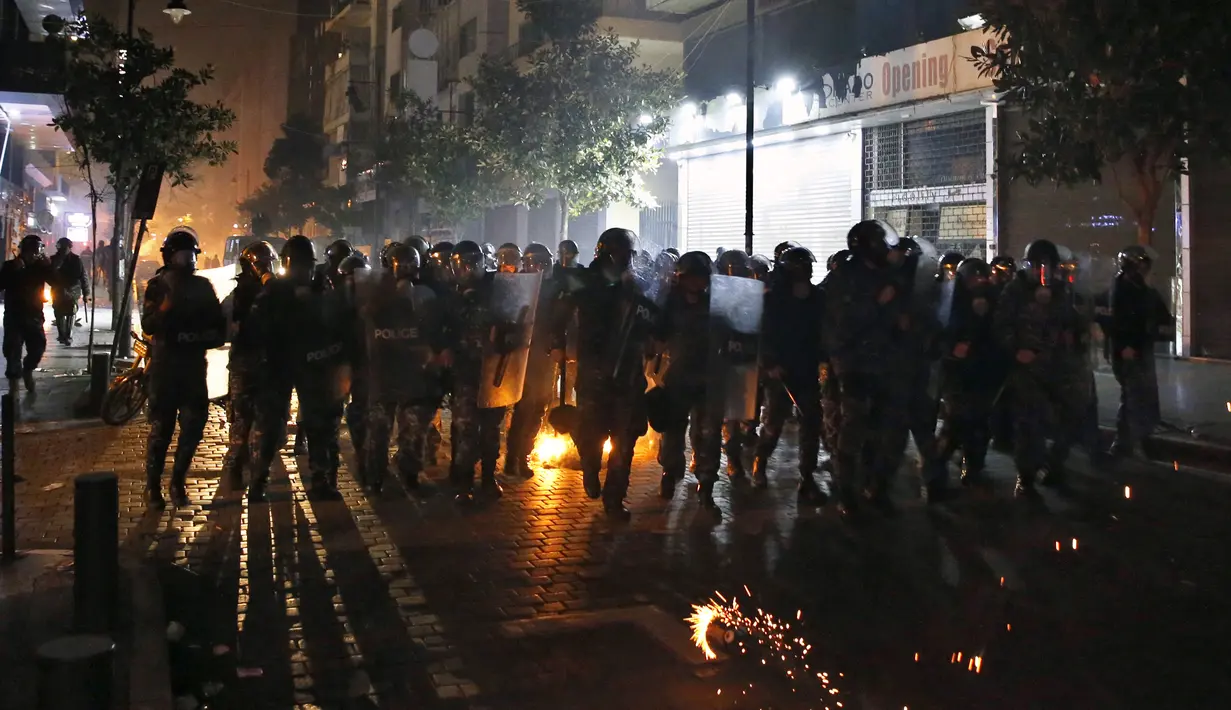 Polisi antihuru-hara berlari ke arah demonstran antipemerintah saat protes menentang elite penguasa di Beirut, Lebanon, Selasa (14/1/2020). Demonstran menganggap elite penguasa gagal mengatasi ekonomi yang menurun tajam. (AP Photo/Bilal Hussein)