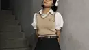Gaya anak sekolahan yang manis ala Zee JKT48. Ia mengenakan atasan berkerah putih lengan pendek dengan aksen kerut, dipadu knitted vest cokelat, dipadu mini pleated skirt hitam dengan belt cokelat. [Foto: Instagram/jkt48.zee]
