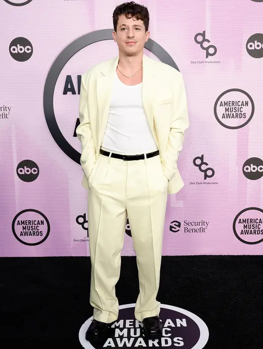 <p>Charlie Puth tampil sederhana dengan setelan blazer dan celana putih. Ia tampak mengenakan dalam putih polos di balik blazernya dan belt ramping berwarna hitam. Foto: Vogue.</p>