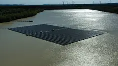 Pemandangan dari udara menunjukkan panel surya dengan turbin angin di kejauhan di pabrik fotovoltaik terapung di danau Silbersee di Haltern, Jerman barat (22/4/2022). Taman surya terapung terbesar di Jerman saat ini sedang dibangun. (AFP/Ina Fassbender)