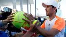 Petenis asal Jerman Mischa Zverev membubuhkan tanda tangan di bola tenis penggemarnya setelah memenangkan pertandingan putaran kedua Australia Terbuka melawan petenis asal AS, John Isner di Melbourne, 17 Januari 2017. (AP Photo/Kin Cheung)