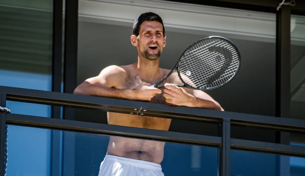 Petenis pria peringkat satu dunia, Novak Djokovic menyapa penggemarnya disela-sela menjalani latihan dari balkon hotel, Adelaide, Australia, Rabu (20/1/2021). (Foto: AFP/Morgan Sette)