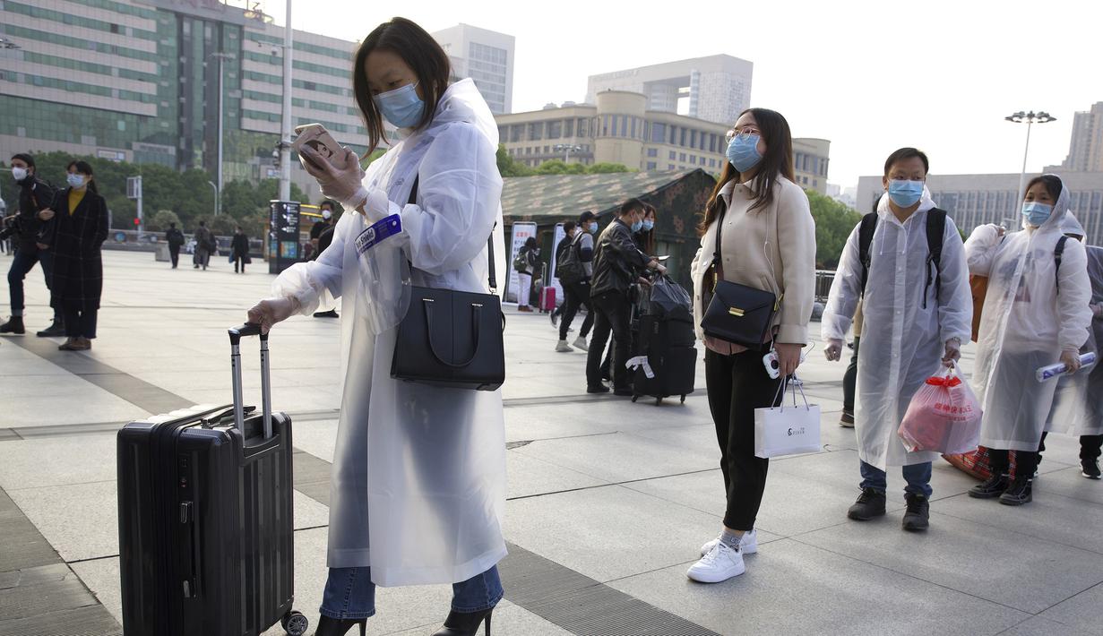 Penumpang yang mengenakan masker dan mantel hujan untuk berkumpul di luar Stasiun Hankou, Wuhan, Provinsi Hubei, China, Rabu (8/4/2020). Setelah 11 minggu lockdown, layanan kereta di kota yang menjadi titik awal pandemi virus corona COVID-19 ini kembali beroperasi. (AP Photo/Ng Han Guan)