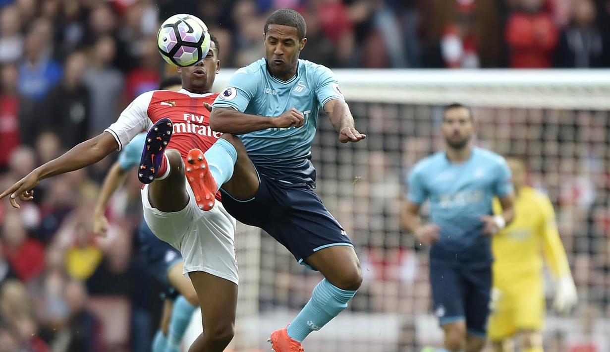 Penyerang Arsenal, Alex Iwobi, berebut bola dengan penyerang Swansea, Wayne Routledge, pada laga Premier League di Stadion Emirates, London, Sabtu (15/10/2016). Arsenal menang 3-2 atas Swansea. (Reuters/Hannah McKay)