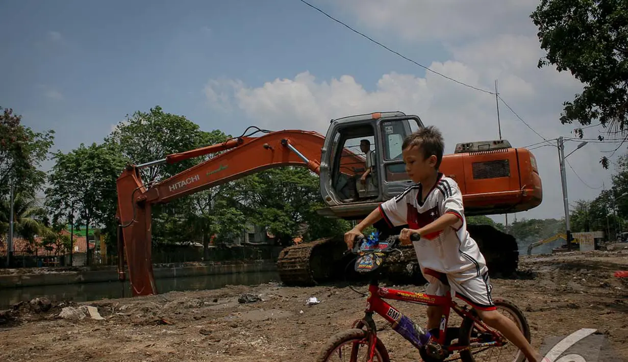 Seorang bocah bersepeda asyik memperhatikan pengerukan Kali Sidang, Jakarta, Jumat (19/9/2014) (Liputan6.com/Faizal Fanani)