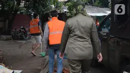 Anggota Satpol PP menghukum warga untuk menyapu jalan saat razia penggunaan masker di Kebon Nanas, Jakarta, Selasa (15/6/2021). Saat kasus positif Covid-19 di Jakarta meningkat, masih banyak warga yang belum menjalankan protokol kesehatan, salah satunya mengenakan masker. (merdeka.com/Imam Buhori)
