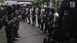 Polisi bersenjata lengkap mengawal sejumlah terduga teroris untuk dihadirkan dalam jumpa pers di Mabes Polri, Jakarta, Jumat (17/5/2019). Sepanjang bulan Mei 2019, tim Densus 88 Antiteror telah menangkap sebanyak 29 terduga teroris jaringan Jamaah Ansharut Daulah (JAD). (Liputan6.com/Johan Tallo)