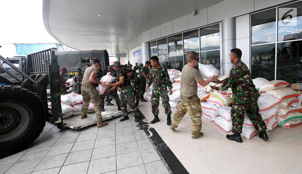 Prajurit TNI dibantu tentara Amerika Serikat mendistribusikan bantuan logistik yang tiba di Bandara Mutiara Sis Al-Jufri, Palu, Sulawesi Tengah, Minggu (7/10). Bantuan asing tiba menggunakan pesawat Hercules. (Liputan6.com/Fery Pradolo)