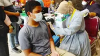 Seorang anak di Pekanbaru disuntik vaksin oleh petugas medis di gedung Kejati Riau. (Liputan6.com/M Syukur)