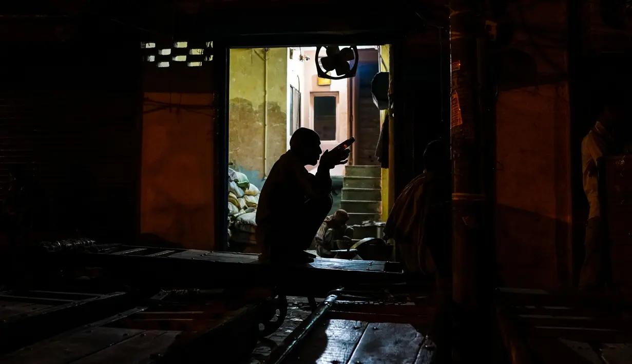 Seorang buruh makan malam di tempat tinggalnya di kawasan tua New Delhi, India (6/3). (AFP Photo/Chandan Khanna)