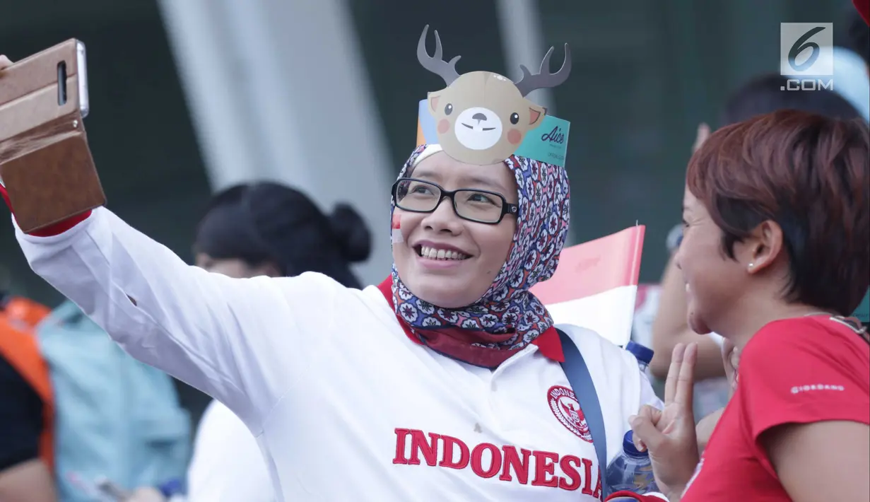 Pendukung tim Indonesia berswafoto jelang menyaksikan seremoni pembukaan Asian Games 2018 di Stadion GBK, Jakarta, Sabtu (18/8). Asian Games 2018 akan berlangsung hingga 2 September, mendatang. (Liputan6.com/Helmi Fithriansyah)
