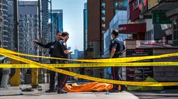 Petugas polisi berdiri dekat salah satu jasad akibat serangan mobil di Toronto bagian utara, Kanada, Senin (23/4). Serangan terjadi ketika sebuah van bergerak ke arah pejalan kaki di jalanan sibuk Toronto. (Aaron Vincent Elkaim/The Canadian Press via AP)