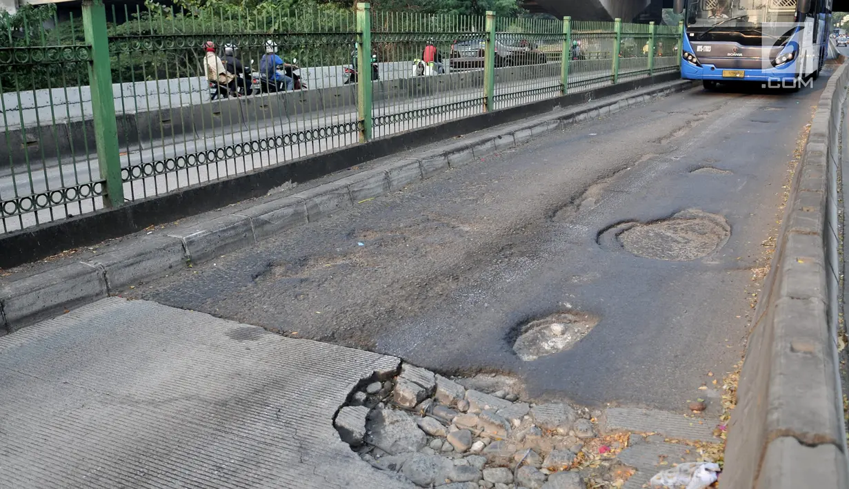 Bus Transjakarta melintas di jalan Galunggung yang rusak dan berlubang di Setia Budi, Jakarta, Selasa (30/7/2019). Jalan yang rusak tersebut mengakibatkan bus melaju dengan kecepatan lambat. (merdeka.com/Iqbal S Nugroho)