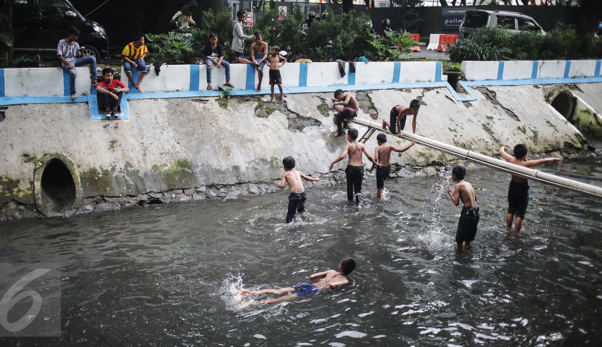 Anak-anak berenang dan bermain air di aliran Kali Gresik di Jalan Muhammad Yamin, Menteng, Jakarta, Minggu (26/2). (Liputan6.com/Faizal Fanani)
