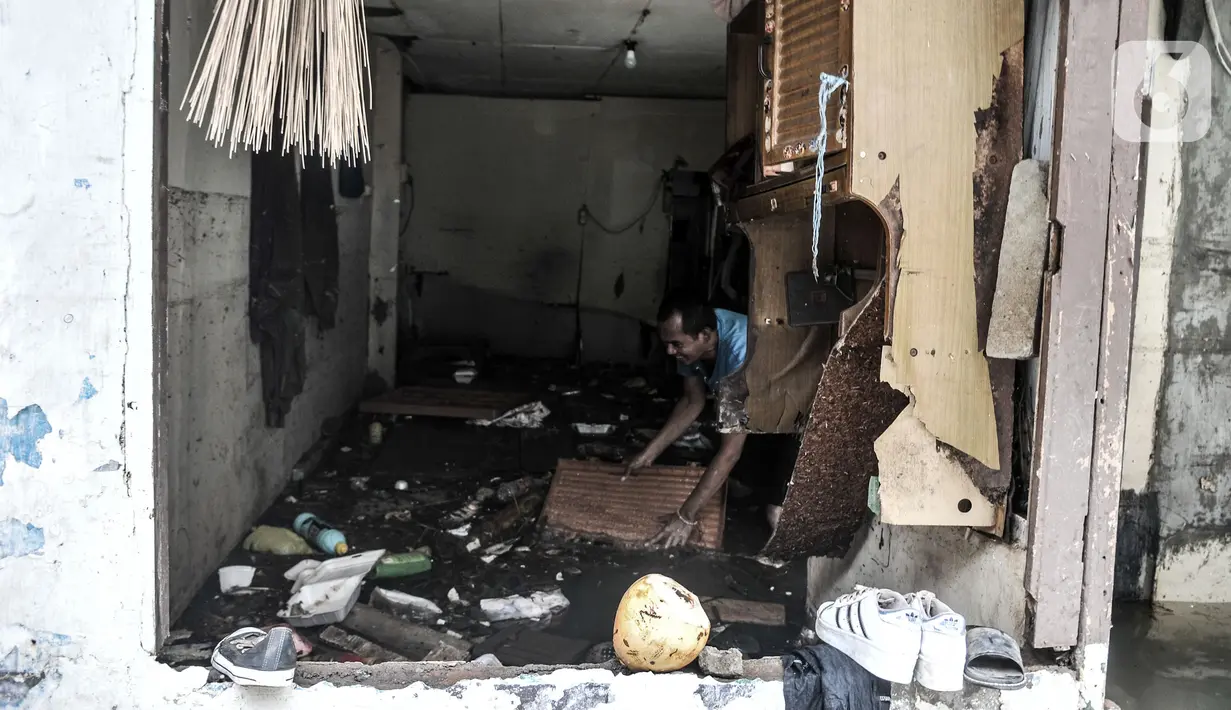 Warga membersihkan sampah di rumahnya yang rusak akibat derasnya arus banjir di kawasan Kemang Timur XI, Jakarta Selatan, Minggu (21/2/2021). Longsor merusak lima rumah warga serta menyumbat aliran kali. (merdeka.com/Iqbal S. Nugroho)