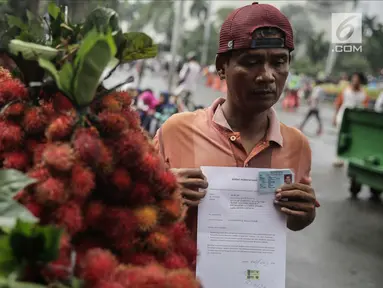 Seorang pedagang buah rambutan menunjukkan surat pernyataan saat ditindak oleh Petugas Dinas Perhubungan di Car Free Day (CFD) di kawasan Bunderan HI, Jakarta, Minggu (4/2). (Liputan6.com/Faizal Fanani)