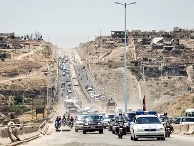 Mobil-mobil pemerintah dan kendaraan militer melintasi jalan raya utama antara Homs dan Hama di Suriah tengah, Rabu (6/6). Pemerintah Suriah membuka kembali jalan raya Homs-Hama setelah ditutup selama hampir tujuh tahun. (AFP/STRINGER)