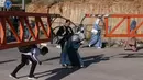 Warga Palestina membungkuk untuk menyeberangi gerbang besi yang didirikan oleh tentara Israel di Hebron, Tepi Barat yang diduduki, pada 13 Mei 2025. (HAZEM BADER/AFP)