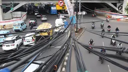 Kendaraan melintas di bawah Instalasi kabel menjuntai di Jalan Dewi Sartika, Jakarta Timur, Sabtu (19/1). Selain mengganggu keindahan kota, kondisi tersebut juga berbahaya karena dapat memicu hubungan pendek arus listrik. (Liputan6.com/Immanuel Antonius)