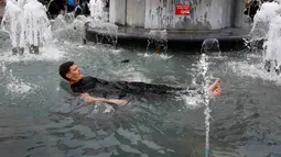 Seorang suporter Inggris berendam di kolam air mancur yang berada di tengah Kota Lille, Prancis (16/6).Aksi ini mereka lakukan setelah mengatahui Timnas Inggris berhasil mengalahkan Wales dalam pertandingan piala Eropa 2016. (REUTERS / Wolfgang Rattay)