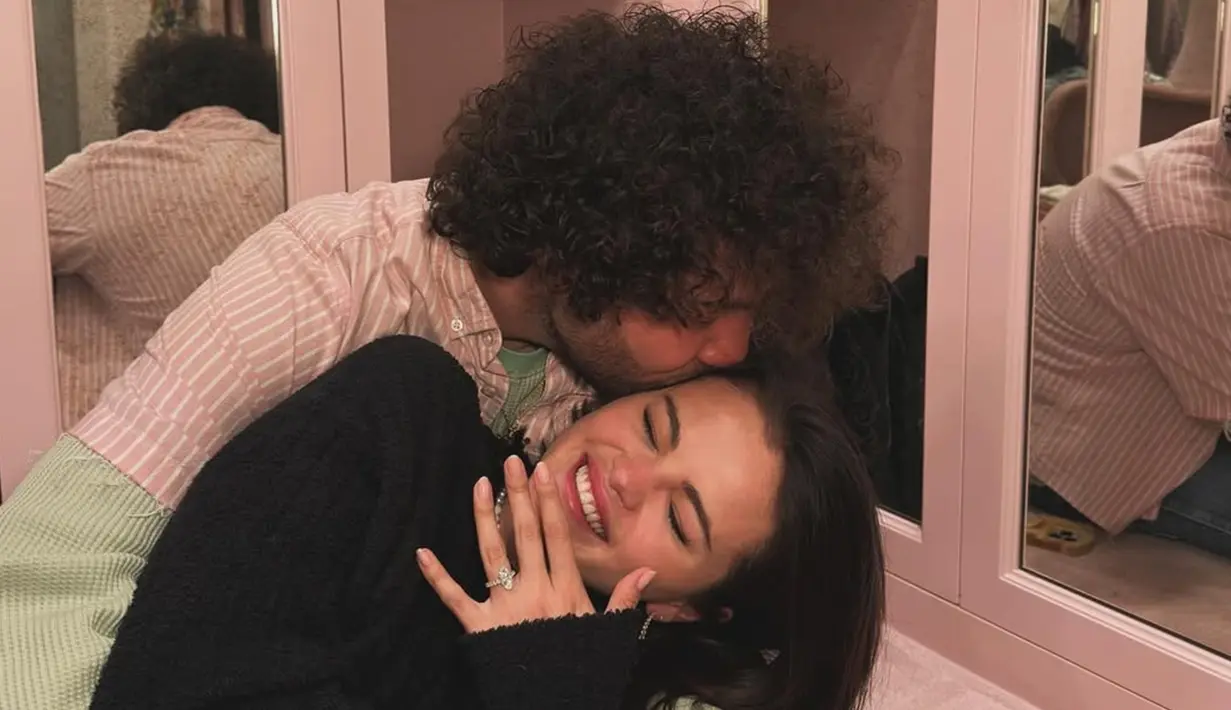 Pada unggahan Instagram, Selena membagikan foto dirinya bersama Benny Blanco dengan cincin pertunangan yang berkilauan di jari manisnya. Para penggemar sudah heboh dengan kabar tersebut, tapi Taylor menambah keseruan dengan komentarnya, "Yes, I will be the flower girl." Respons Taylor ini langsung disambut dengan antusias oleh penggemar, yang membayangkan kehadirannya dalam pernikahan Selena sebagai gadis bunga yang tak terlupakan. (Liputan6.com/IG/@selenagomez)