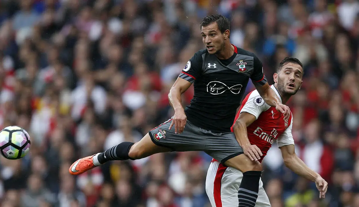 Bek Southampton, Cedric Soares, membuang bola dari jangkauan striker Arsenal, Lucas Perez. Pada laga ini wasit mengeluarkan tujuh kartu kuning, dua untuk Arsenal, sisanya untuk pemain Southampton. (AFP/Ikimages)