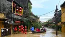 Orang-orang menyusuri jalan yang terendam banjir dengan perahu setelah hujan deras di Hoi An, Vietnam, Kamis 30 Oktober 2025. Sedikitnya sembilan orang tewas dan lima lainnya masih dinyatakan hilang. (NHAC NGUYEN/AFP)