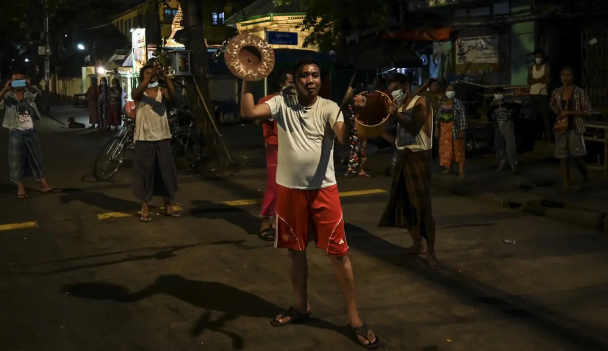 Orang-orang membuat keributan dengan memukul-mukul simbal dan wajan setelah seruan untuk protes keluar di media sosial di Yangon, Myanmar, 3 Februari 2021. Kudeta militer Myanmar terus memicu protes warga dengan membunyikan klakson mobil, menyalakan lampu ponsel, dan memukul-mukul panci. (STR/AFP)