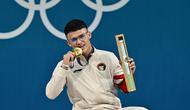 Peraih medali emas dari Indonesia, Rizki Juniansyah, berpose di podium setelah pertandingan angkat besi kelas -73kg putra selama Olimpiade Paris 2024 di South Paris Arena di Paris, pada 8 Agustus 2024. (Miguel MEDINA/AFP)