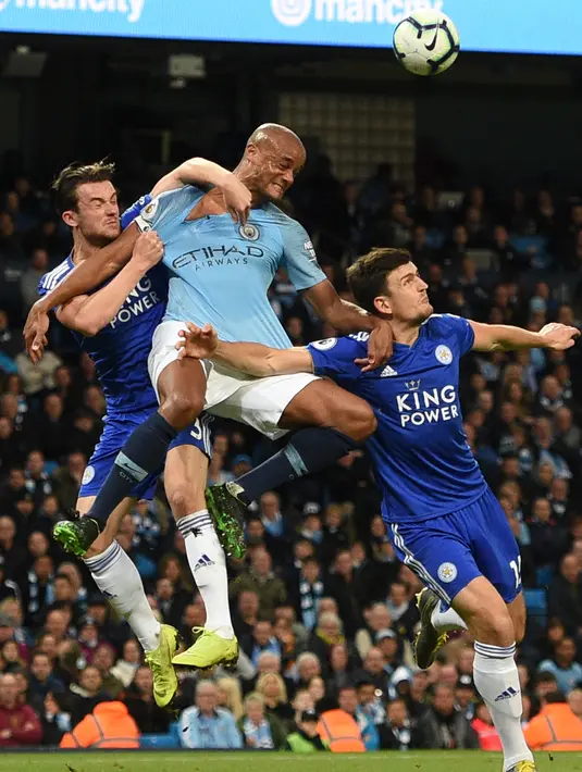 Bek Leicester City, Harry Maguire (kanan) bersama rekannya Ben Chilwell berebut bola udara dengan bek Manchester City, Vincent Kompany pada pertandingan Liga Inggris di Stadion Etihad pada 6 Mei 2019. (AFP Photo/Oli Scarff)
