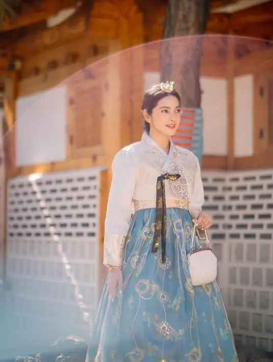 Nabila Syakieb bak putri Korea kenakan hanbok putih dengan rok biru yang punya bordiran emas. [@nsyakieb85]