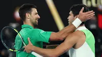 Novak Djokovic memberikan selamat kepada Carlos Alcaraz setelah berhasil juara Australian Open 2026 yang dilangsungkan di Melbourne Park pada (1/2/2026) sore WIB. (AFP/Martin Keep)