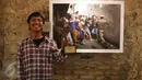 Juara 1 Kategori General News, Immanuel Antonius berpose di depan karyanya berjudul "Penertiban Kampung Pulo" sambil memegang trofi Anugerah Pewarta Foto Indonesia (APFI) ke-VI di Gedung Merdeka, Bandung, Sabtu (9/4). (Liputan6.com/Immanuel Antonius)