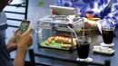 Pengunjung mengambil foto ular saat makan di sebuah kafe ular bernama 'Tokyo Snake Center' di distrik fashion Harajuku, Tokyo, 14 Agustus 2015. Sekali kunjungan, pengunjung hanya perlu membayar sekitar Rp108 ribu. (REUTERS/Toru Hanai)