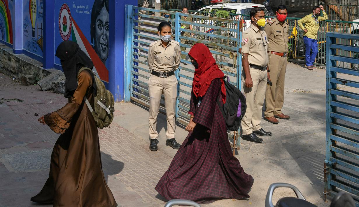 Polisi berjaga-jaga ketika siswa sekolah menengah negeri dan perguruan tinggi pra-universitas untuk wanita memasuki tempat institut pendidikan di Bangalore (16/2/2022). (AFP/Manjunath Kiran)
