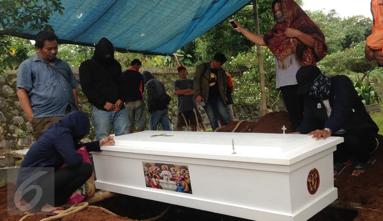 Peti jenazah Ramlan Butarbutar saat ingin diturunkan di TPU Kalimulya III, Depok, Jawa Barat, Jumat, (30/12). Ramlan merupakan sopir angkot di Pulo Gadung dan telah memiliki tiga anak. (Liputan6.com/Ady Anugrahadi)