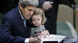 Menteri Luar Negeri AS John Kerry menggendong cucunya Isabelle Dobbs-Higginson saat menandatangani surat Perjanjian Paris tentang perubahan iklim di Markas Besar PBB, Manhattan, New York, AS (22/4). (REUTERS / Carlo Allegri)