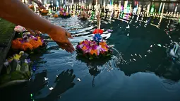 Orang-orang melepaskan lampion mengambang di kolam selama festival Loy Krathong di Bangkok (8/11/2022). Loy Krathong adalah ritual melarung wadah berbentuk lotus yang didalamnya diberi sesajen, lilin dan dupa. (AFP/Lillian Suwanrumpha)