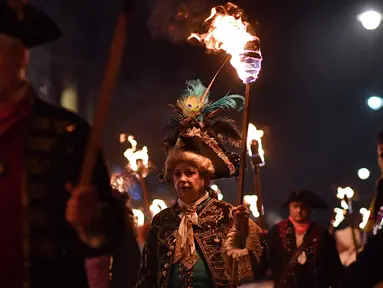 Peserta melakukan pawai melintasi jalan dalam perayaan Bonfire Night di Sussex Timur, Inggris, Selasa (5/11/2019). Setiap tahunnya pada tanggal 5 November, warga Inggris menggunakan kostum, berdandan, berkumpul, lalu melakukan pawai ke seluruh penjuru kota sambil membawa obor. (Ben STANSALL/AFP)