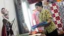 Pegawai merapikan kain batik yang dipajang pada acara Relaunching Batik Keris Online di Bekraf Habibie Festival 2017 Jakarta. Batik Keris mulai merambah ke Online hadir dengan tampilan dan fitur yang terbaru. (Liputan6.com/Pool)