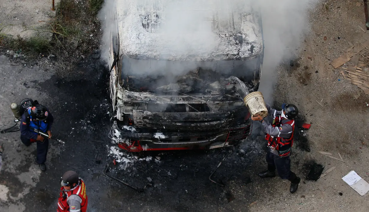 Petugas pemadam kebakaran berusaha memadamkan api dari truk yang dibakar para demonstran saat menggelar aksinya di Caracas, Venezuela (24/4). (AP Photo/Fernando Llano)